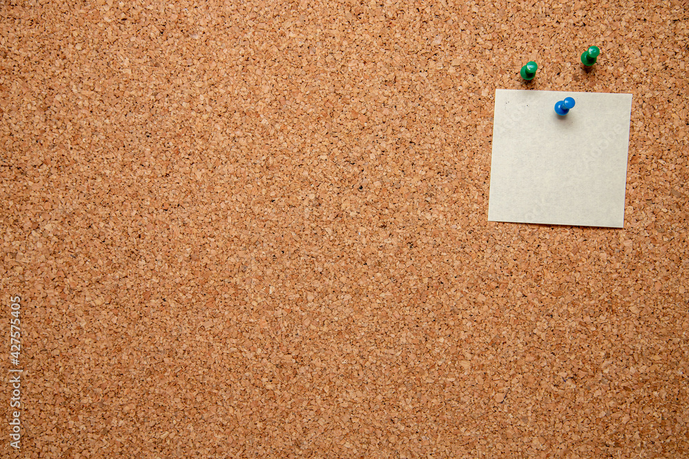 Aufkleber closeup shot of three pins and an empty white paper with space for text on a corkboard
