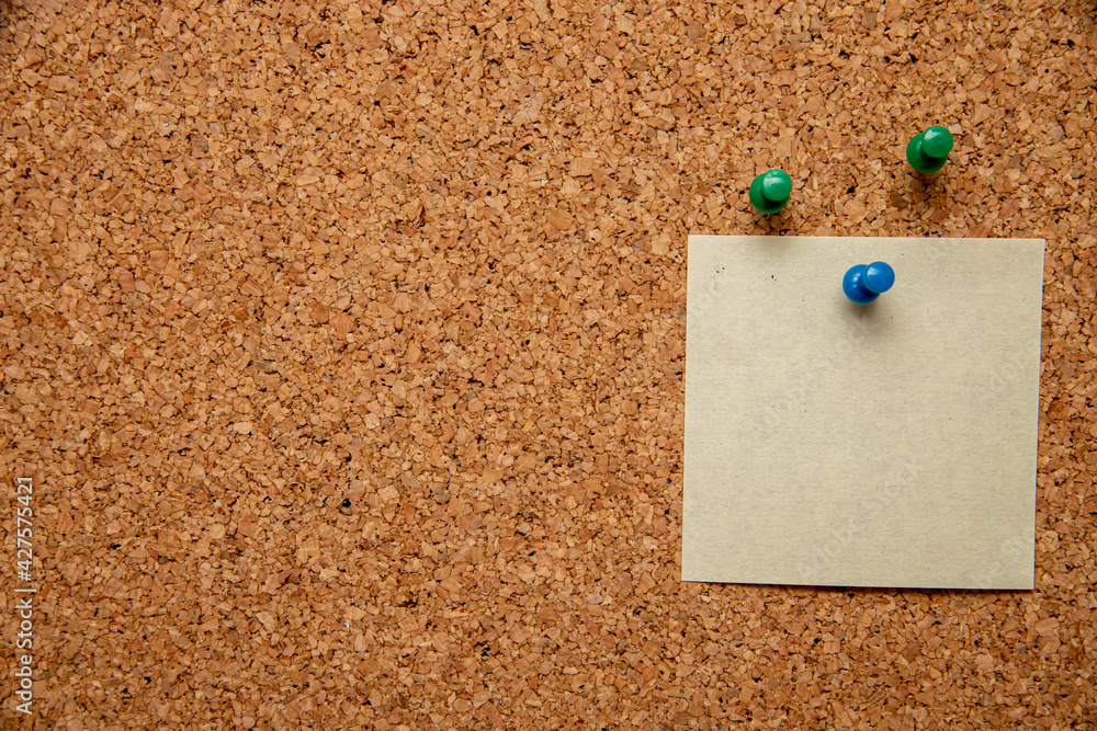 Canvas Prints Closeup shot of three pins and an empty white paper with space for text on a corkboard