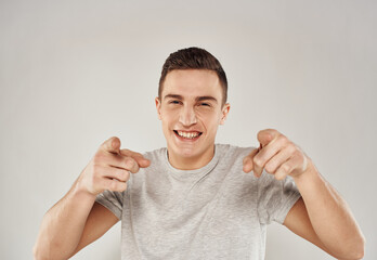 A cheerful man in a white T-shirt gestures with his hands emotions close-up