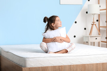 Morning of little girl sitting on bed with comfortable mattress - obrazy, fototapety, plakaty