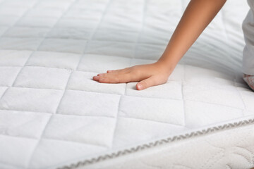 Little girl touching soft orthopedic mattress, closeup