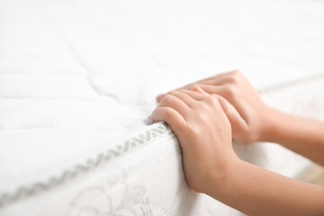 Little girl touching comfortable mattress, closeup