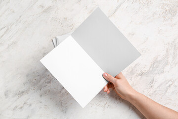 Hand with blank brochures on light background