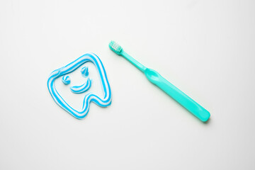 Toothbrush and tooth made of paste on white background