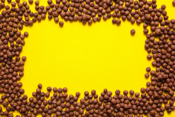 Frame made of chocolate corn balls on color background