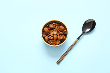 Bowl with chocolate corn flakes and spoon on color background