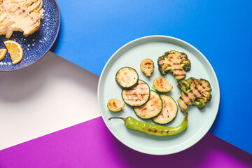 Plates with tasty grilled vegetables on color background