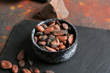 Bowl with cocoa beans on grunge background