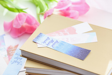 Books with bookmarks and flowers on light background