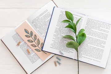 Books with bookmark and branch on light background