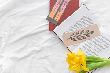 Books with bookmarks and flower on bed
