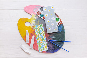 Bookmarks and artist's supplies on light wooden background
