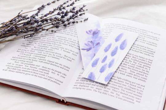 Book with bookmarks and lavender on bed, closeup