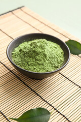 Bowl with powdered matcha tea on bamboo mat