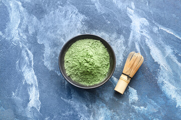 Bowl with powdered matcha tea and chasen on color background