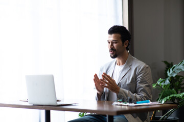 Attractive business man in suits and headsets smiling while working on desktop computer at modern office desk . Customer service assistant working in office. VOIP Helpdesk headset