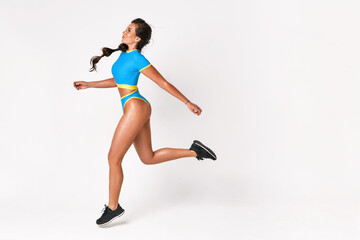 A sportive woman runs in a blue suit on a white background. Long jump. fitness. athletics. aerobics