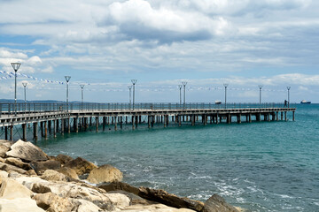 Obraz premium Sea pier on Molos promenade with street lamps, flag garlands and scenic cloudscape, Limassol, Cyprus