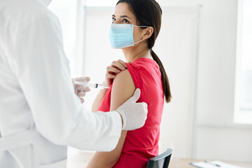 doctor holding a syringe injected into the shoulder of a woman patient covid vaccination
