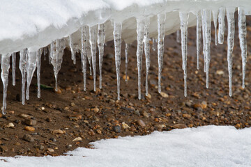 icicles hang from the ice floe over the pebbly shore