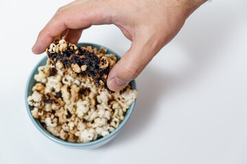 spoiled burnt popcorn in a blue cup. man's hand close up