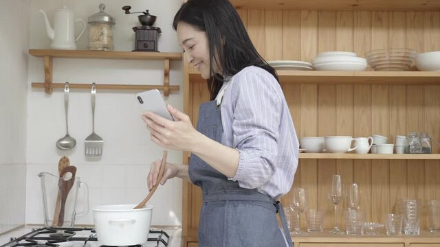 スローモーション　スマホを見ながら料理をするミドル女性