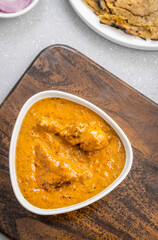 butter chicken, an Indian creamy chicken gravy served in a white bowl with roti or naan