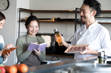 Image of a beautiful student and a bearded chef attending a cooking class. Copy space available.