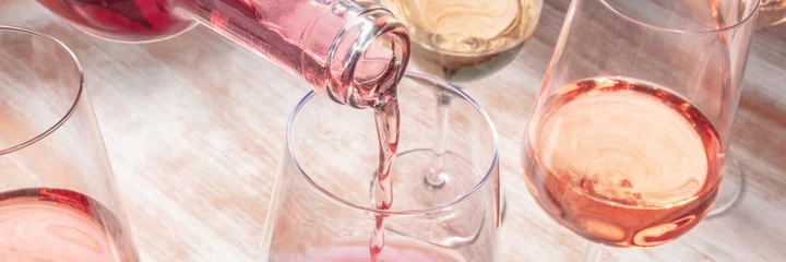 Rolgordijnen Rose wine pouring panorama with various glasses © laplateresca