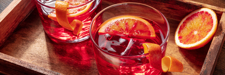 Negroni cocktails with blood oranges panorama on a rustic background