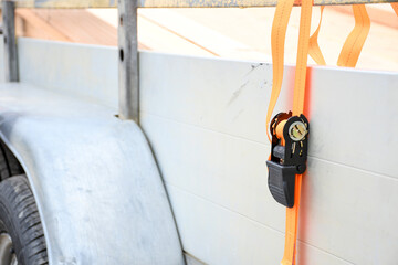 Trailer strop or strap in orange nylon and metal, object helping for holding stuff , storage and transport for safty and security.
