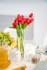 vase with a bouquet of red tulips on the festive table. serving the table with appetizers, canapes, salads in jars. Catering. restaurant business.