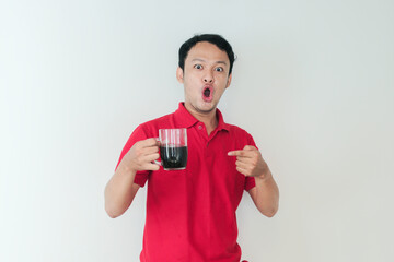Young Asian man holding a cup of coffee standing over isolated white background with shock and wow...