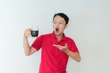 Young Asian man holding a cup of coffee standing over isolated white background with shock and wow expression