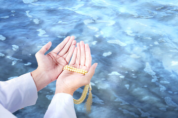 Muslim man praying with prayer beads on his hands