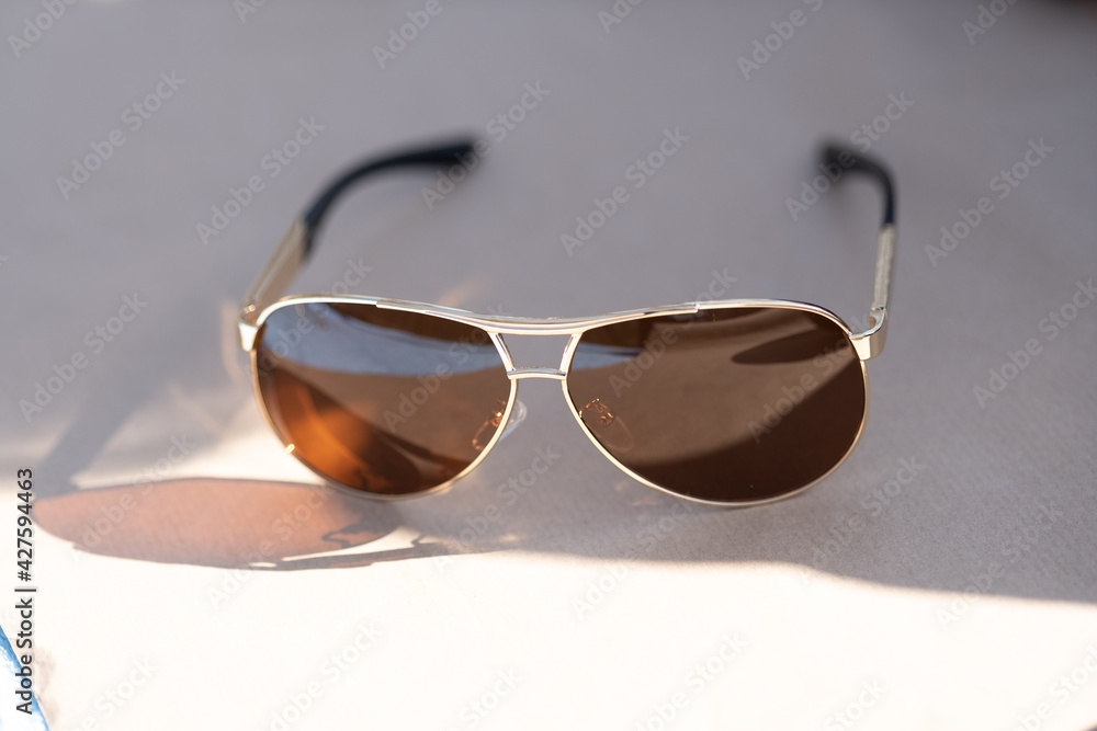 Wall mural aviator sunglasses model with big brown lenses shoot outside in a summer day closeup . selective foc