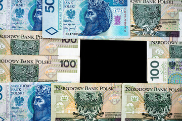 Polish banknotes of PLN 100 and PLN 50 on a black background. Photo taken under soft artificial light
