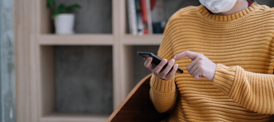 Woman in medical mask using mobile phone. Isolation at home