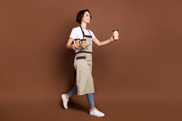 Fototapeta na wymiar Full length body size view of lovely cheerful girl carrying bringing coffee time break isolated over brown color background