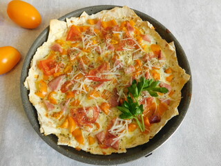 homemade pizza with cheese, bacon and herbs on pita bread.