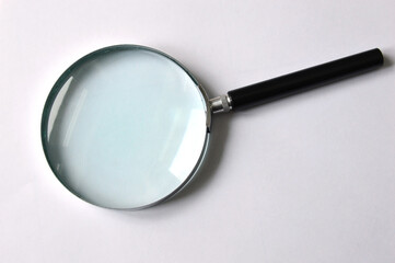 Magnifier with black handle on a white background. Magnifying glass. View from above