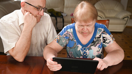 An elderly couple use modern gadgets to surf the Internet