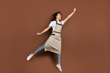 Fototapeta na wymiar Full size photo of carefree crazy girl raise fist up look empty space open mouth isolated on brown color background
