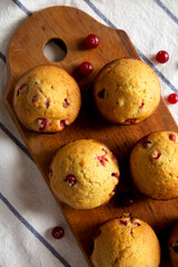 Homemade Cranberry Muffins with Orange Zest on a rustic wooden board on cloth, view from above. Flat lay, overhead, top view.