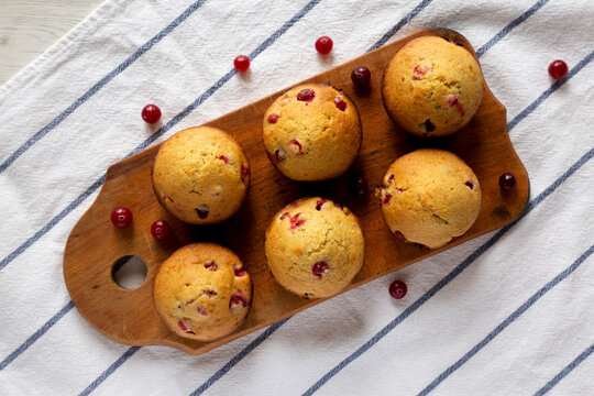 Homemade Cranberry Muffins With Orange Zest On A Rustic Wooden Board On Cloth, Overhead View. Flat Lay, Top View, From Above.