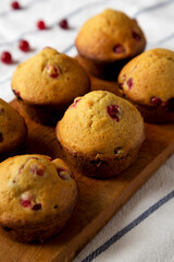 Homemade Cranberry Muffins with Orange Zest on a rustic wooden board on cloth, side view. Close-up.