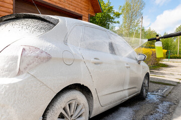 Manual unknown car wash with high pressure water equipment pump at home backyard outdoors on bright...
