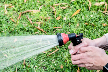 Watering the lawn with the garden hose. Hands holding water hose