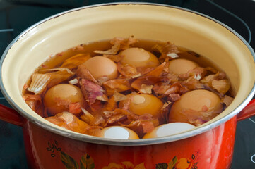 Saucepan with water and onion skins on the stove. Eggs are boiled and painted for Easter. Preparation for the celebration.
