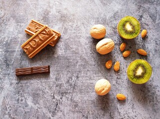 Fototapeta na wymiar Sweets, fruits and nuts on a blue background. Chocolate, cookies, kiwis, almonds, walnuts